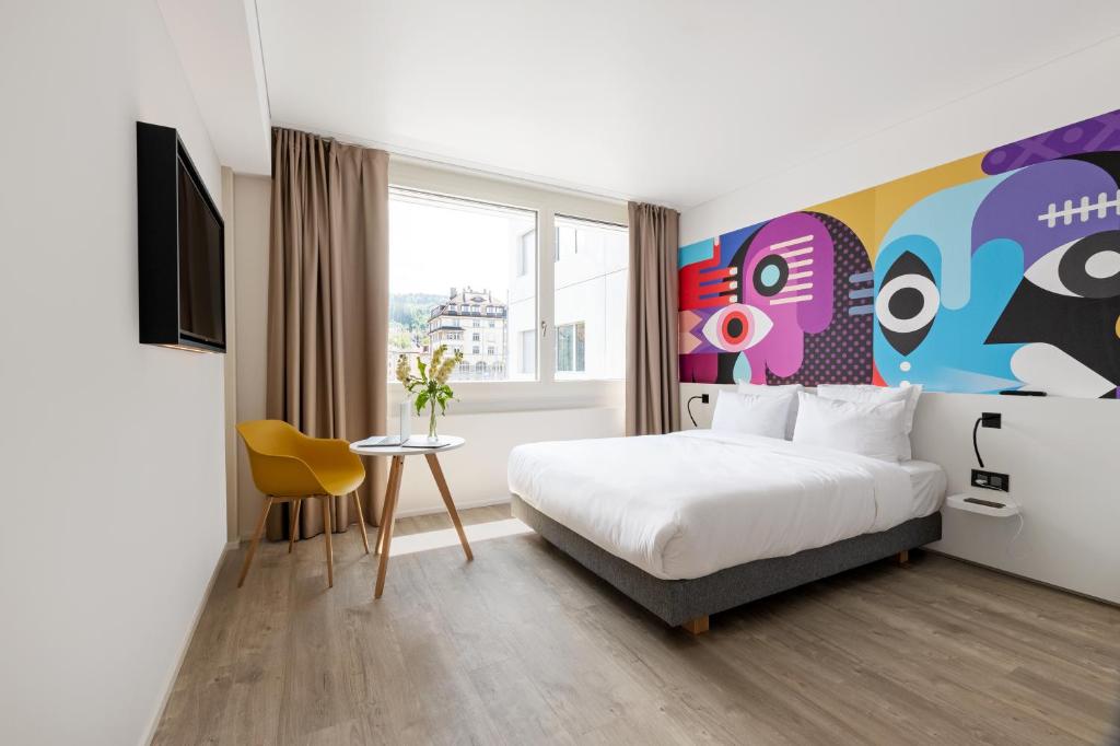 圣加仑B&B HOTEL St Gallen的酒店客房设有一张床,墙上挂有绘画作品