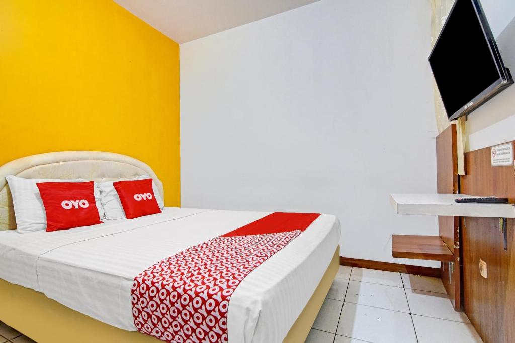 雅加达SUPER OYO 90422 Mall Of Indonesia的一间卧室配有一张带红色枕头的床和一台电视。