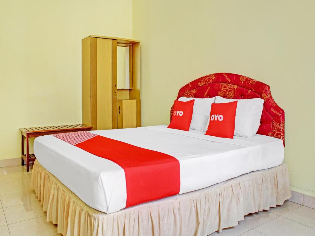 帕朗卡拉亚OYO 90423 Hotel Aman的一间卧室配有一张带红色和白色枕头的大床