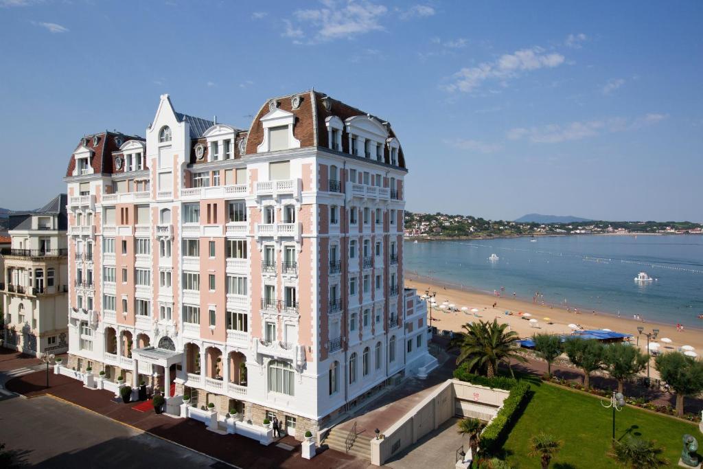 圣让-德吕兹海水浴温泉大酒店的一座白色的大建筑,后面有海滩