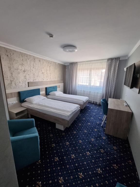 特尔古穆列什Vila El Passo的酒店客房带两张床和一张桌子以及椅子。