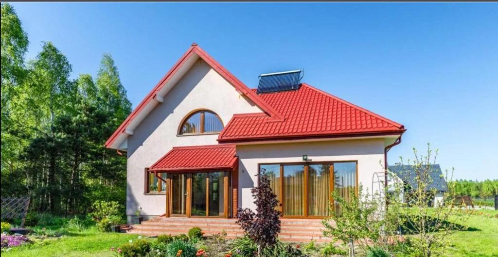 LudwinAgroturystyka przy lesie的一间白色的小房子,有红色的屋顶