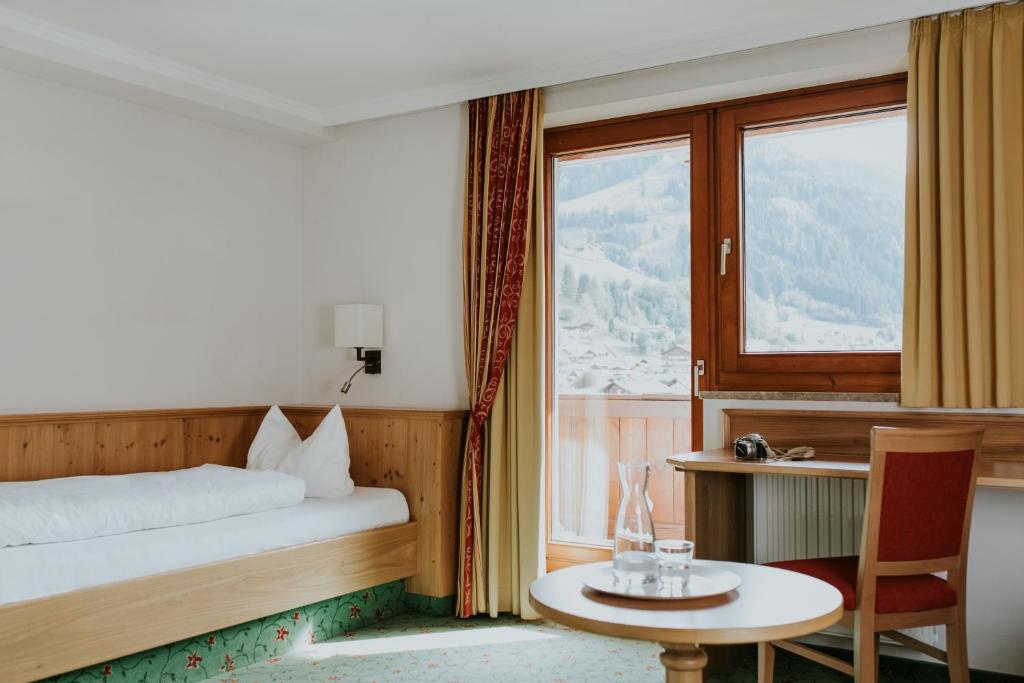 格罗萨尔Hotel Tauernhof的一间卧室配有一张床、一张桌子和一个窗户。