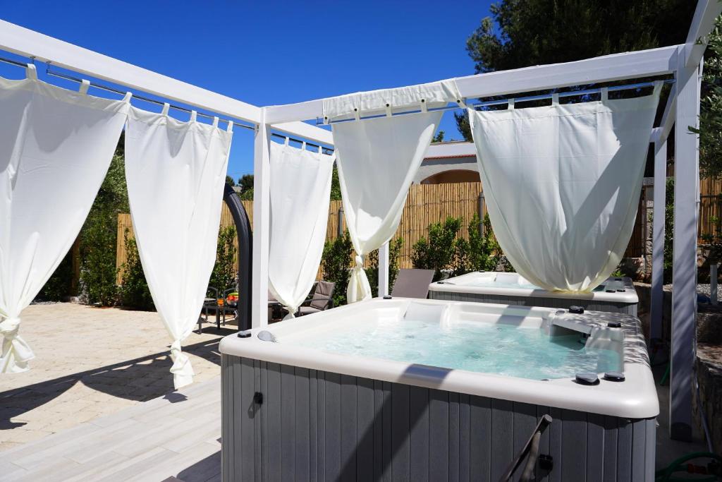 塞尔瓦迪法萨诺VILLA NUCCI by Apulia Hospitality的后院的热水浴池配有白色窗帘