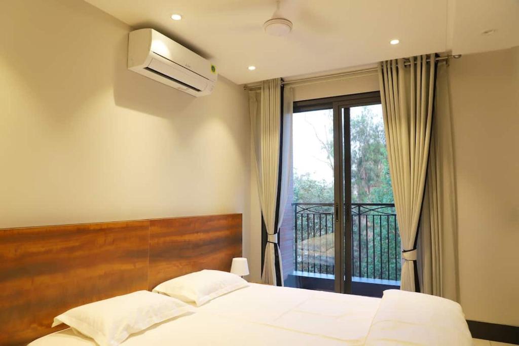 新德里Apt# ONE-FOUR-TWO - with Lift - High Speed Wifi - Smart TV的一间卧室设有一张床和一个阳台的窗户。