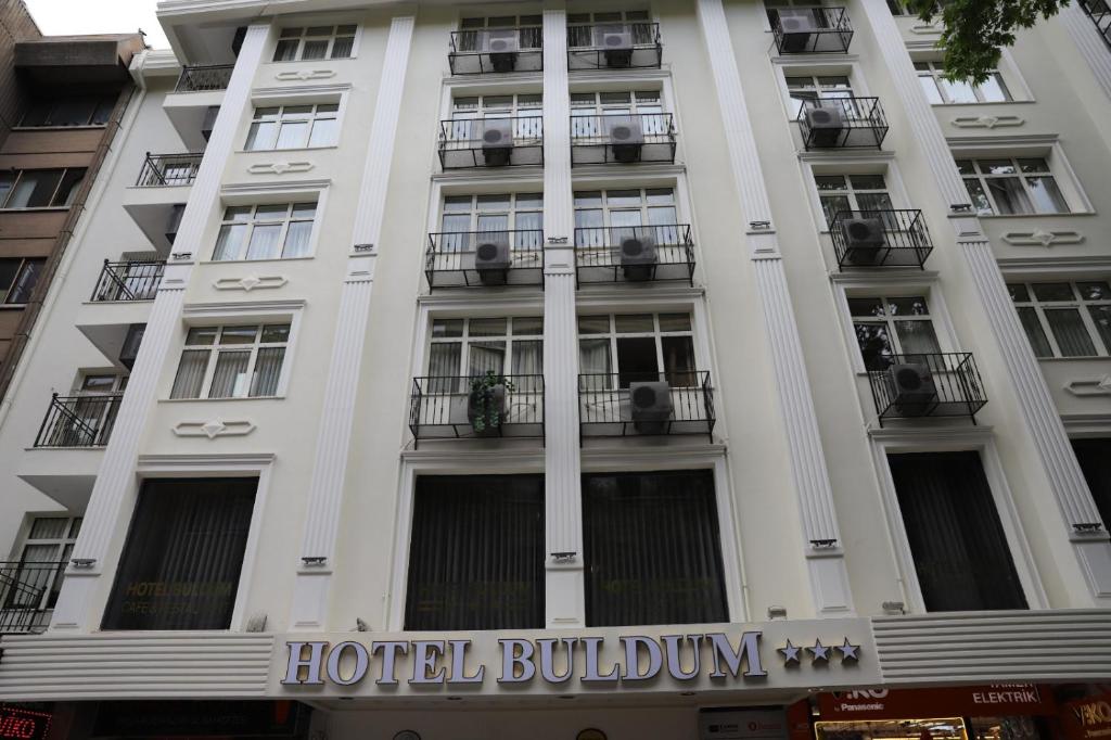 安卡拉Buldum Otel的酒店大楼设有阳台,上面有标志