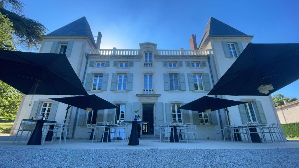 LempautChâteau de la Bousquetarie的前面有桌子和伞的建筑
