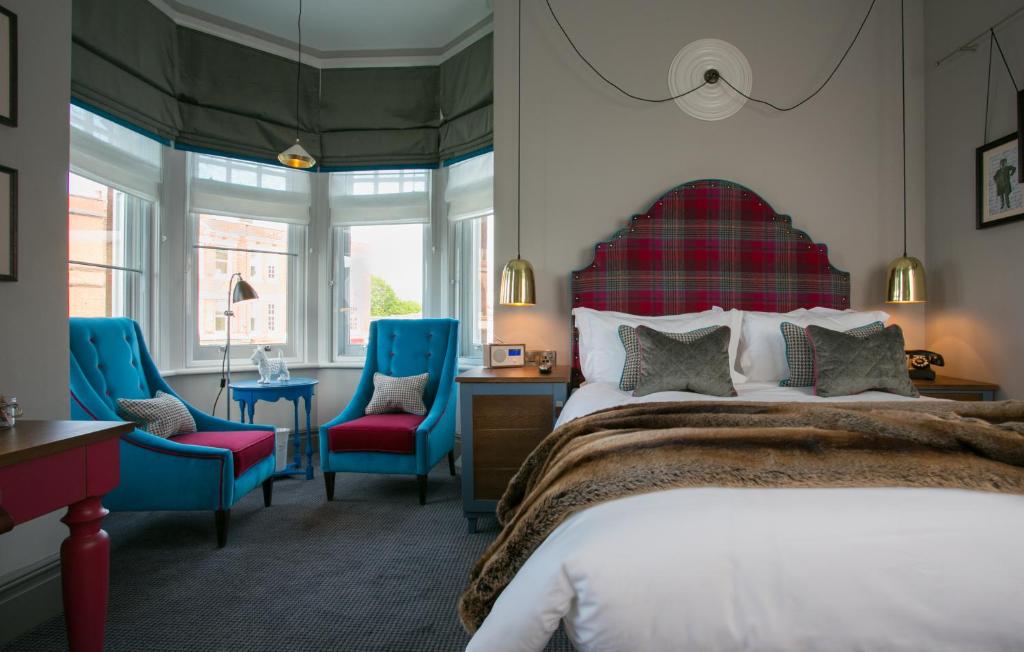 伦敦道格与弗克斯旅馆的一间卧室配有一张床和两张蓝色椅子
