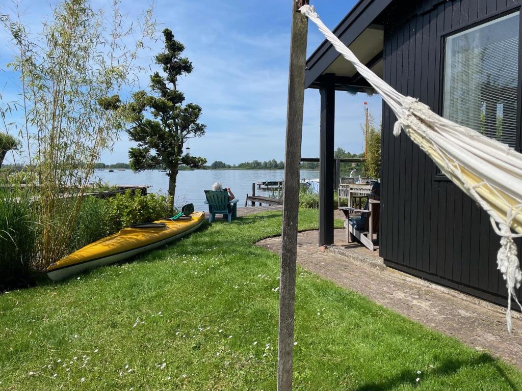 ReeuwijkThe Outpost Lakehouse- enjoy our house at Reeuwijkse Plassen - near Gouda的小屋旁的吊床,草地上有小船