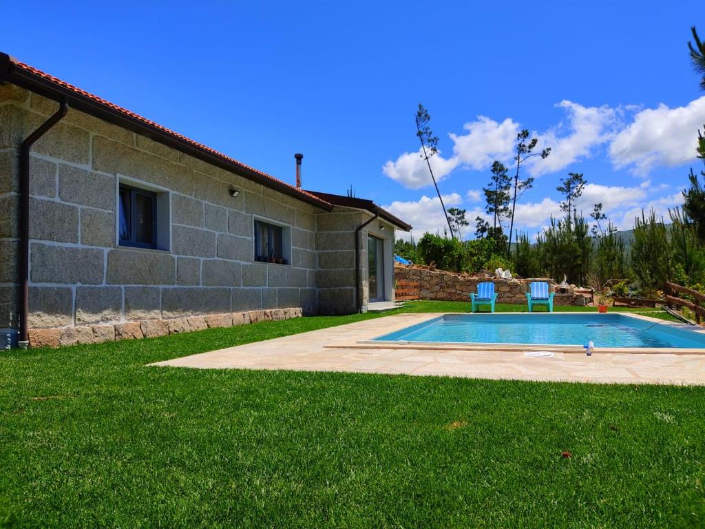 吉尔斯Casa do Vale - Casa da Montanha - Gerês的房屋前带两把椅子的游泳池