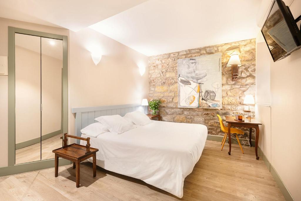 圣塞瓦斯蒂安Hotel Okako San Sebastian的卧室配有白色的床和石墙