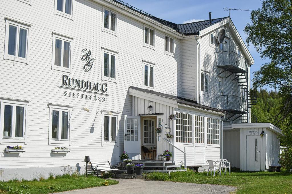 RundhaugRundhaug Gjestegard的白色的建筑,上面有读跑步车的标志