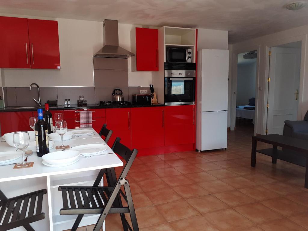 韦尔卡尔-奥韦拉Casa Rural Los Tres Amigos for holidays and business的厨房配有红色橱柜和白色的桌椅