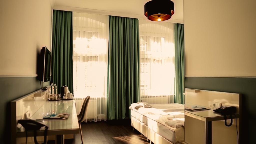柏林柏林普恩斯酒店的一间卧室配有一张床、一张书桌和一个窗户。