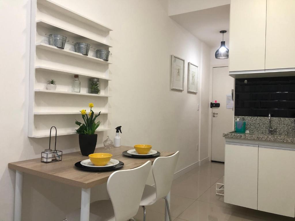 科蒂亚Flat Granja Viana - espaço e conforto的厨房配有木桌和白色椅子