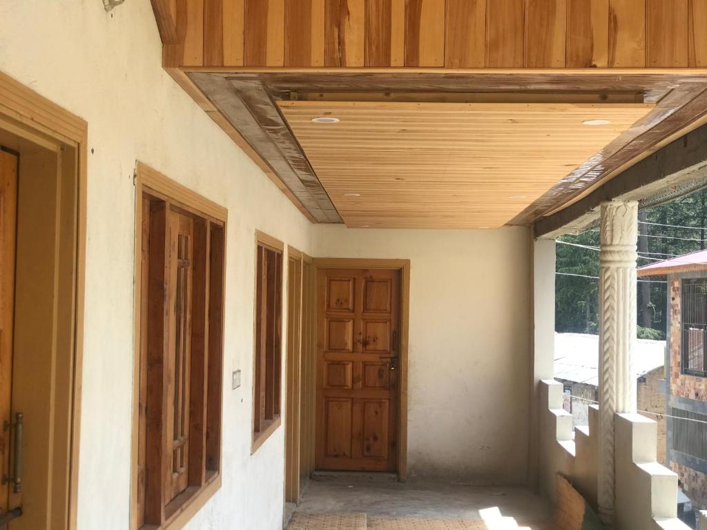 阿尤比亚ViveGee Cottage Khanipur Ayubia的一条空的走廊,有木天花板和门