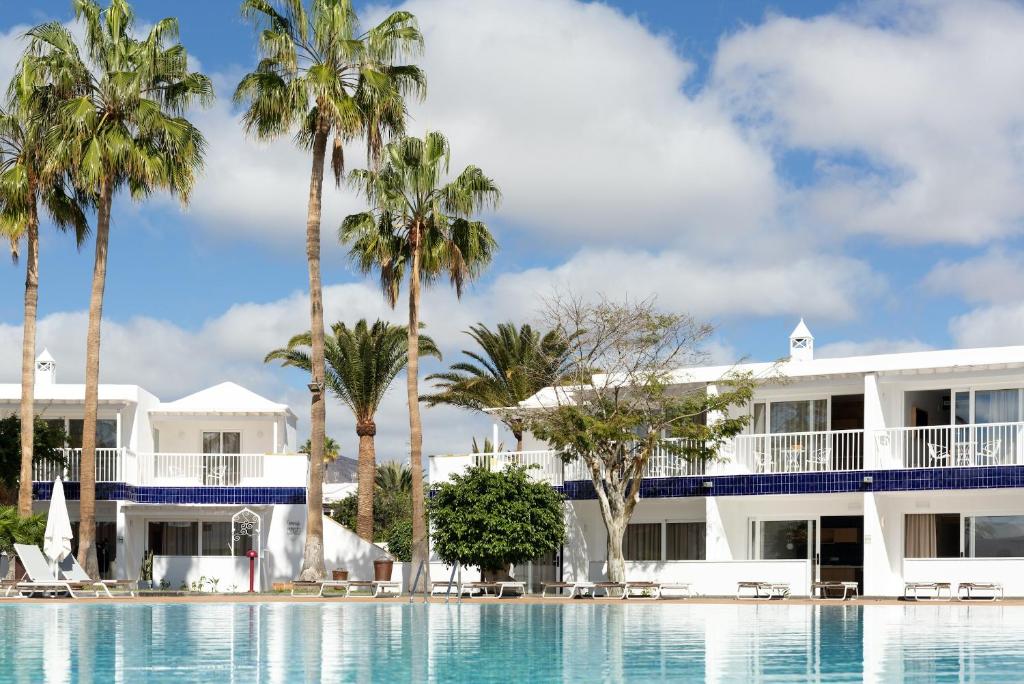 卡门港Barcarola Club的享有棕榈树度假村和游泳池的景色