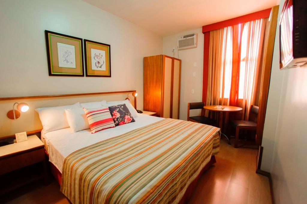 尤西德福拉César Inn Juiz de Fora Hotel的酒店客房设有一张床、一张书桌和窗户。