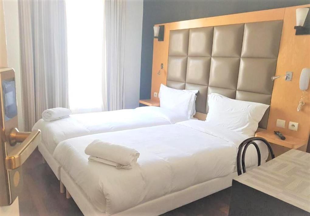 巴黎法兰西18号酒店的一间卧室配有两张带白色床单的床和大型床头板。