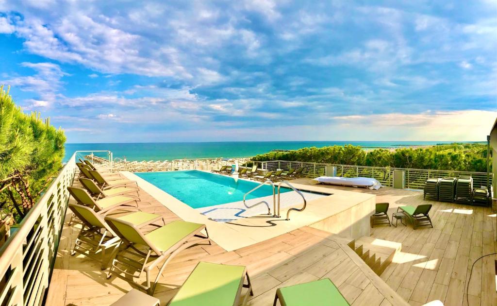 伊拉克里亚马勒Park Hotel Pineta & Dependance Suite的一个带游泳池和椅子的阳台,享有海景