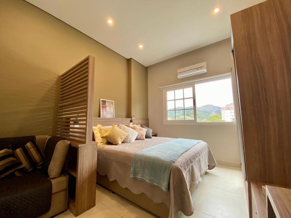 伊泰帕瓦Happy Flat Itaipava - Granja Brasil的一间卧室设有床、窗户和沙发