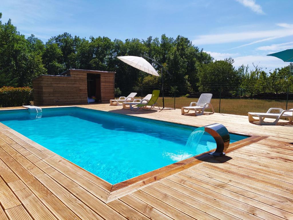 SoturacLa maison d'iréne的一个带椅子和遮阳伞的木制甲板上的游泳池