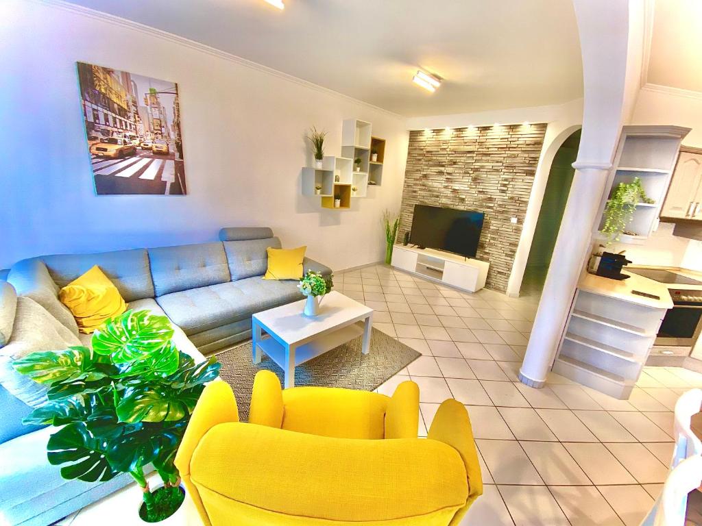 塞格德Mirell Apartman的客厅配有蓝色的沙发和黄色的椅子