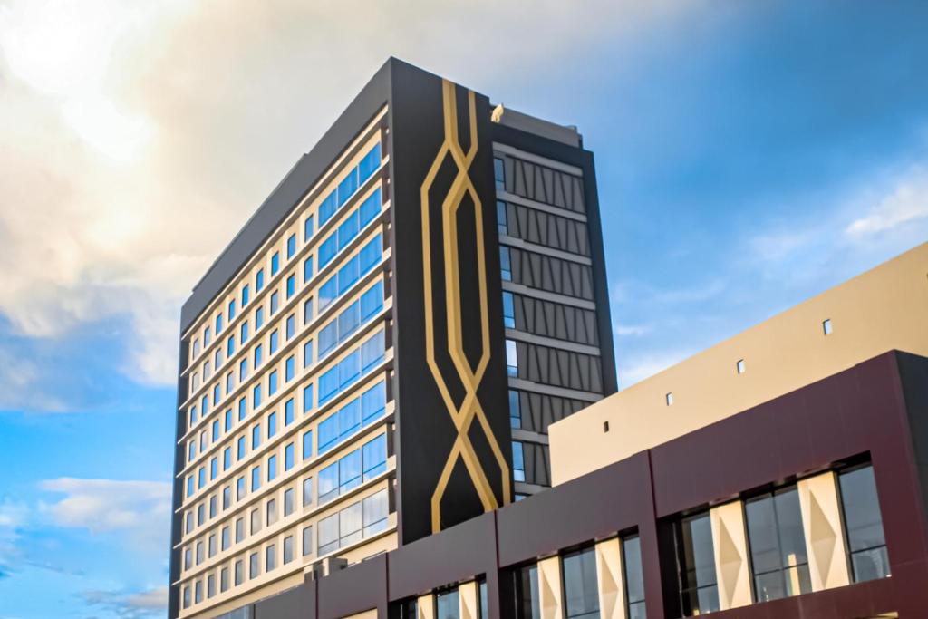 TobadiSuni Hotel and Convention Abepura managed by Parkside的一座高大的黑色建筑,上面设计着黄色