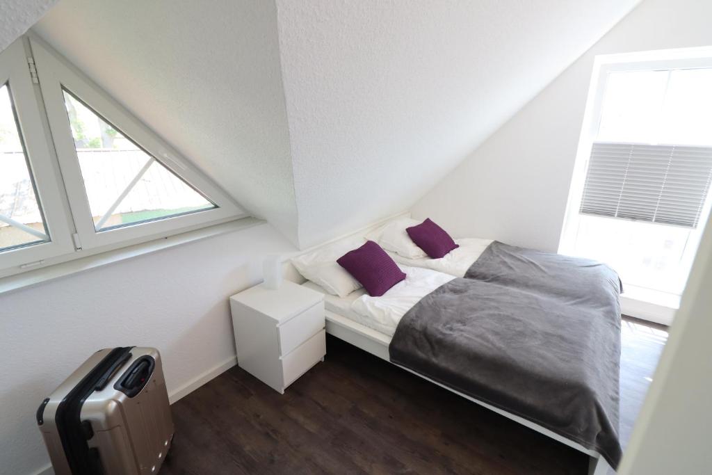 库克斯港Ferienhaus im Angerdorf的一间卧室配有一张带紫色枕头的床和行李箱