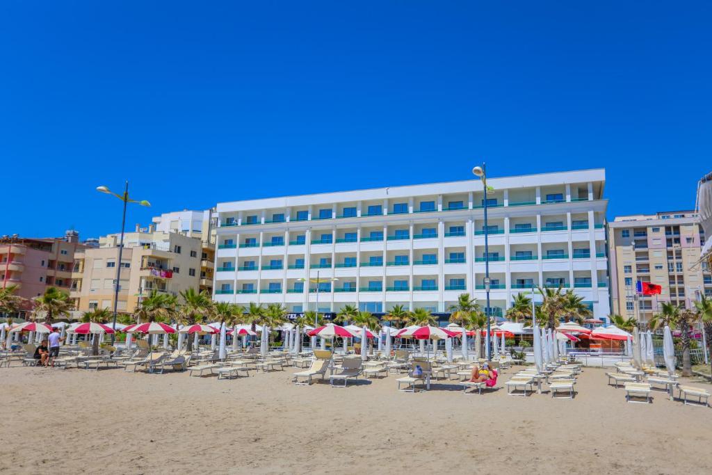 都拉斯Hotel Vivas的一个带椅子和遮阳伞的海滩和一座建筑