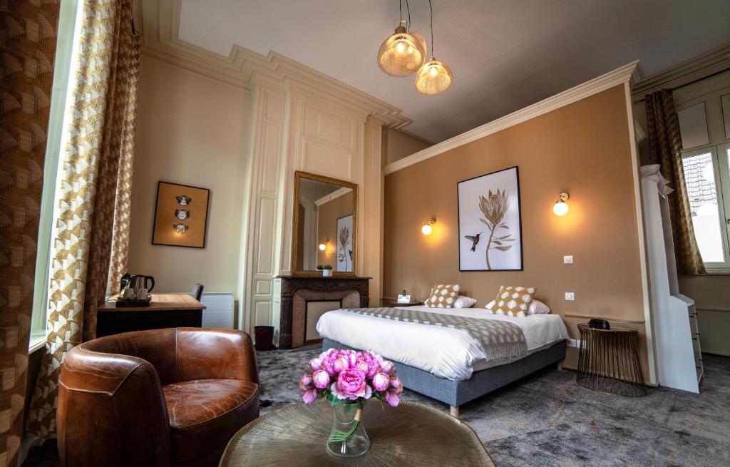 蒙特勒伊Logis Hôtel & Restaurant - Les Hauts de Montreuil的配有床和鲜花桌的酒店客房