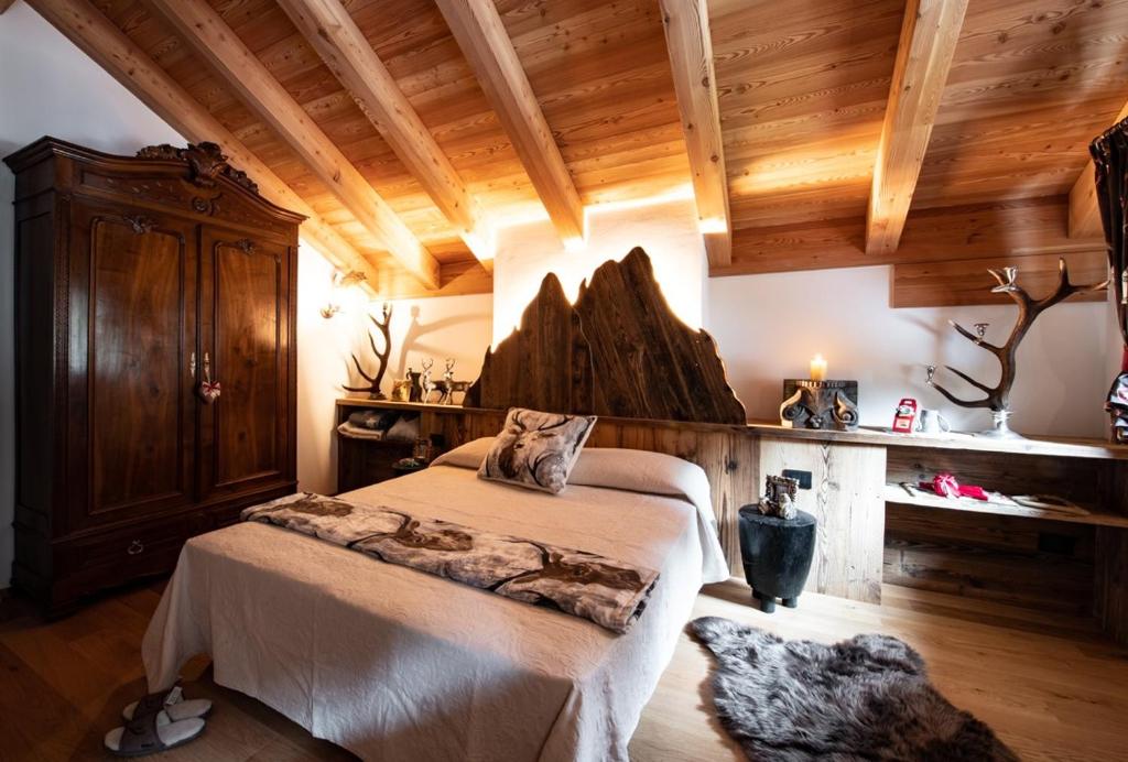 坎皮泰洛迪法萨Dolomiti Chalet degli Abeti的一间带一张床的卧室,位于带木制天花板的房间内