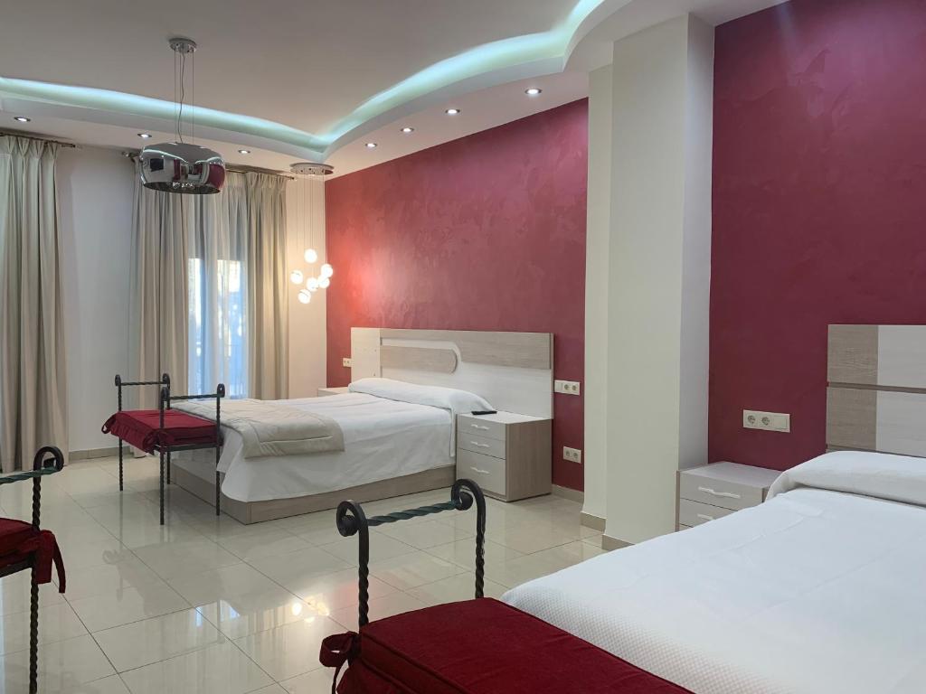 巴埃萨Hostal Poeta Machado的一间卧室设有两张床和红色的墙壁