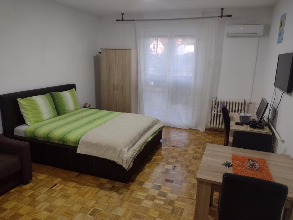 巴尼亚科维利亚查Apartman Vesna的一间卧室配有一张带绿色床单的床和一张桌子