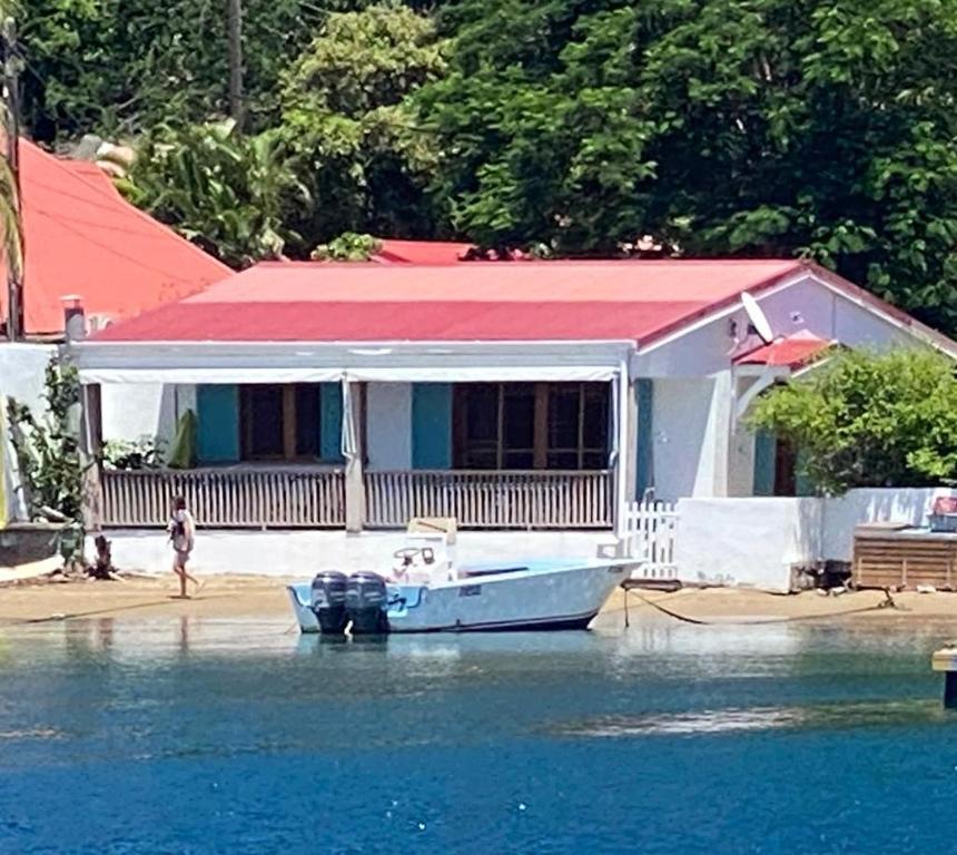 豪特尔Villa GRENADINE Vue panoramique, les pieds dans l'eau的水面上房子前面的船