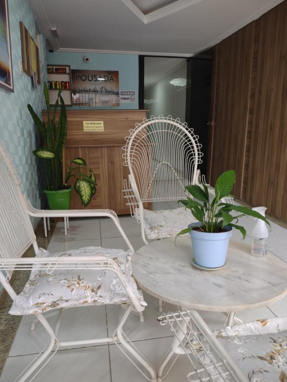 瓜拉派瑞Pousada Solar da Praia的一间房间,配有两把椅子和一张桌子,种植了盆栽植物