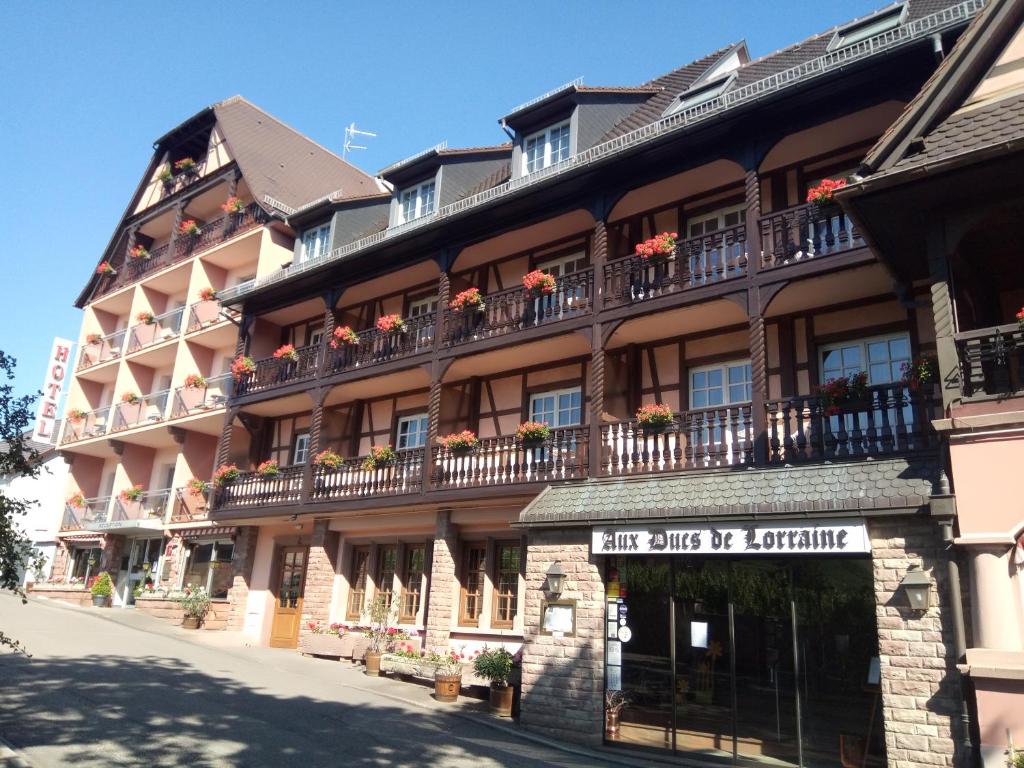 圣伊波利特Hotel Munsch Restaurant & Wellness, Colmar Nord - Haut-Koenigsbourg的一座带阳台的大型建筑,鲜花盛开