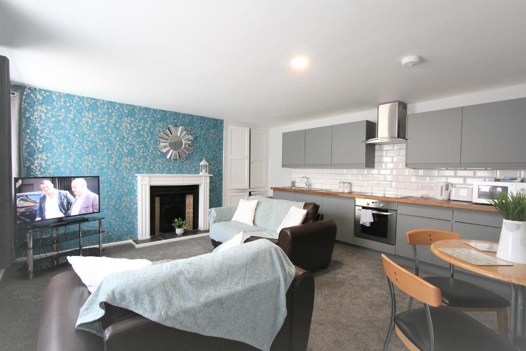切尔滕纳姆Albion Street Serviced Apartments的厨房以及带沙发和电视的客厅。