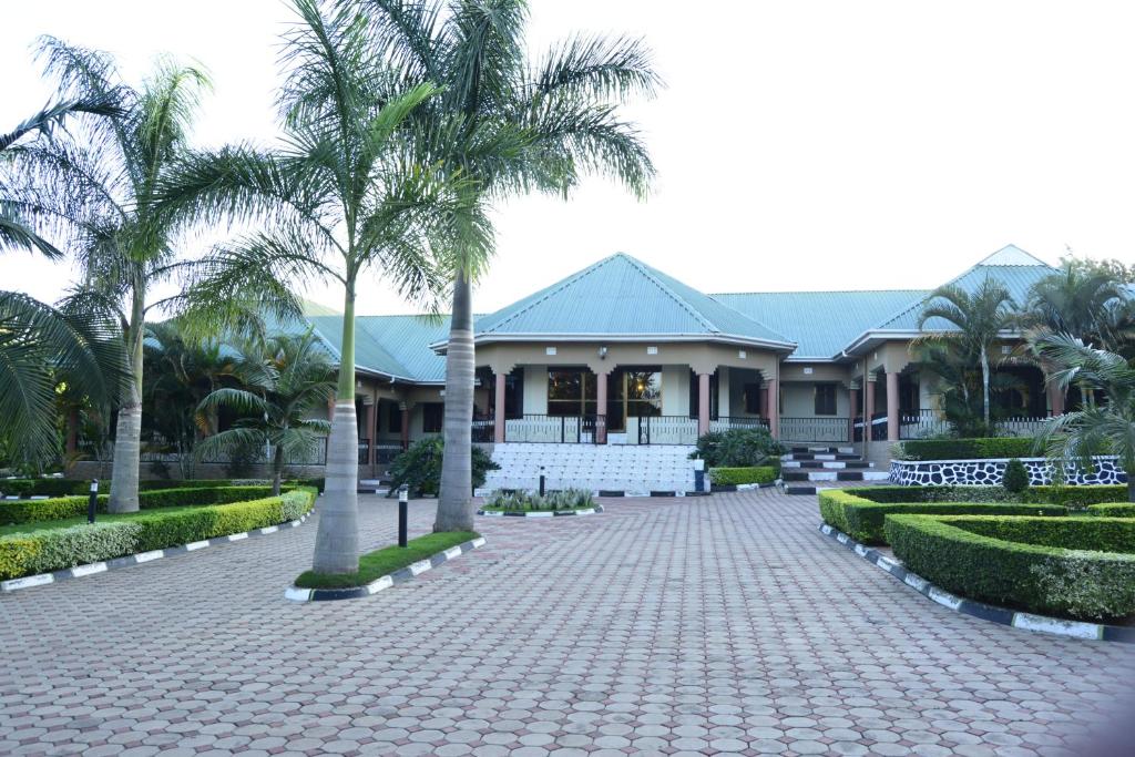 NkoarangaAfrica Lodge Arusha的车道前有棕榈树的房子