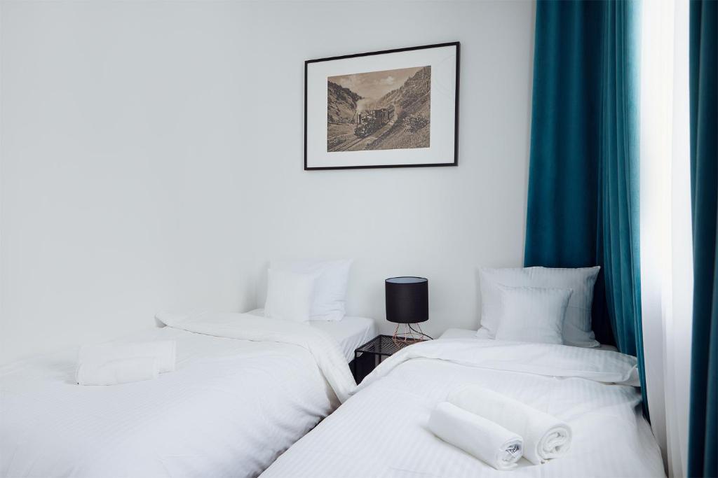科沙林Stary Koszalin Hostel &amp; Hotel Services的配有蓝色窗帘的客房内的两张单人床