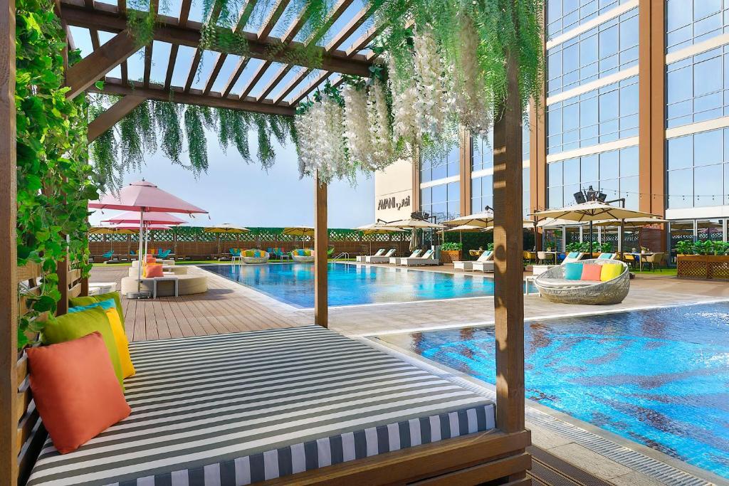 迪拜Avani Ibn Battuta Dubai Hotel的酒店游泳池设有床,大楼