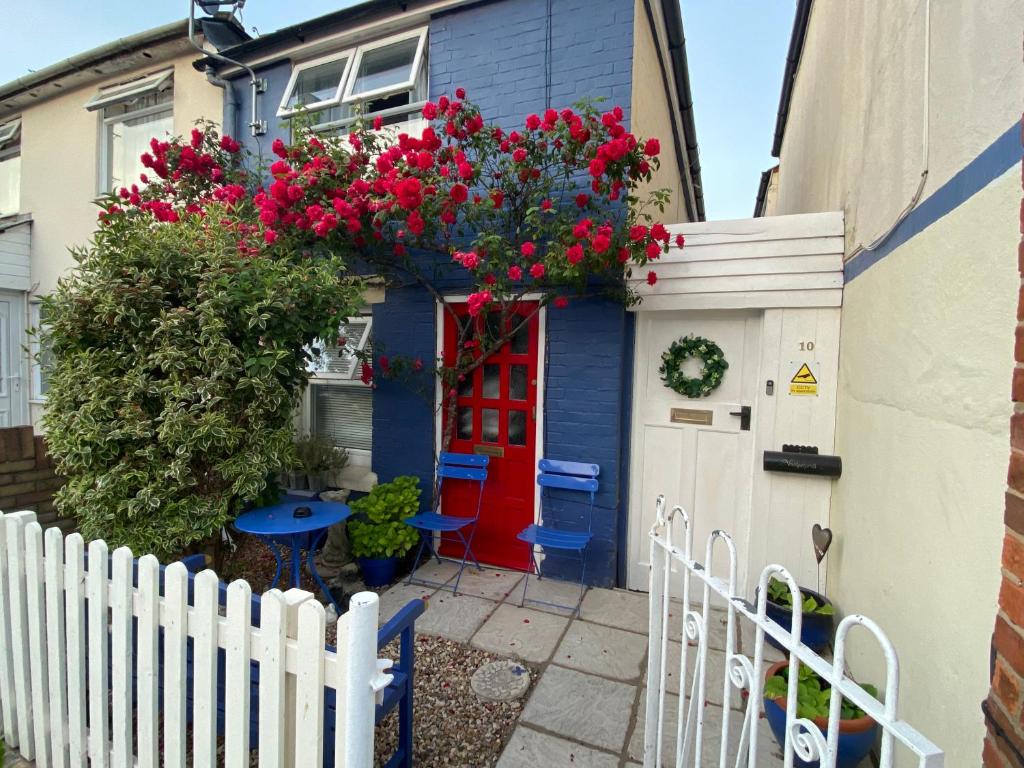 科尔切斯特Prince Cottage的蓝色的房子,有鲜花的红色门