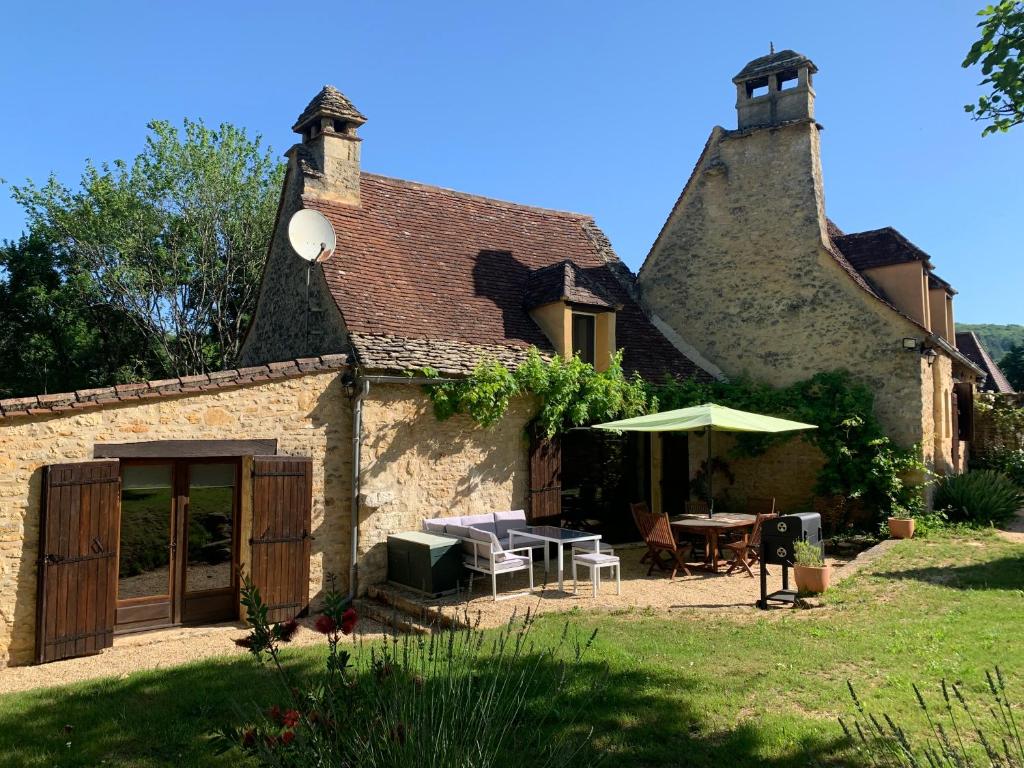 勒比格Gîte - Le Reclaud du Noyer的院子里带桌子和雨伞的房子