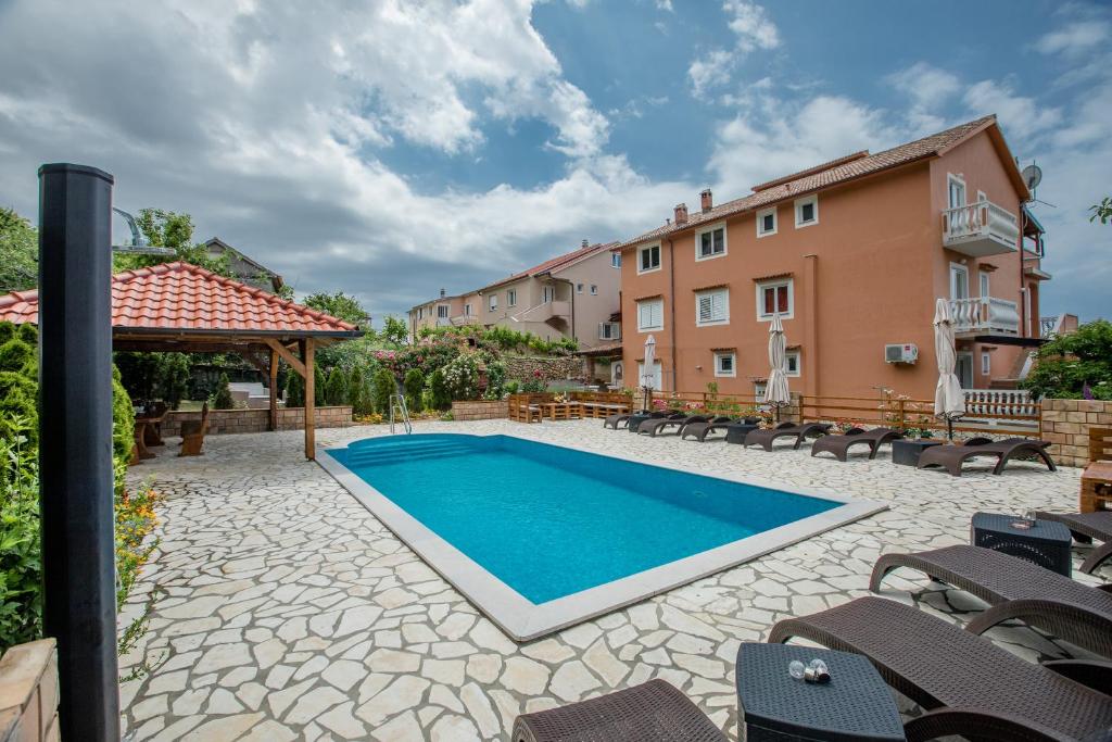 拉布Apartments Šćerbe 3103的一座带椅子的庭院内的游泳池以及一座建筑