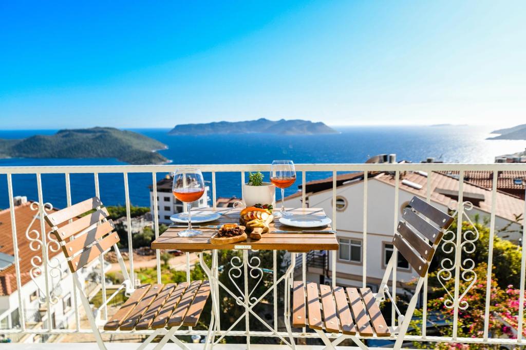 卡斯Kybele Suites的俯瞰大海的阳台的桌子和酒杯