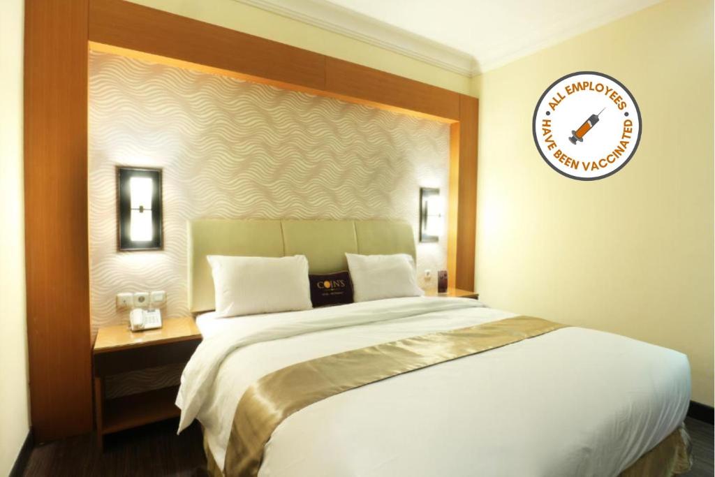 雅加达Coins Hotel Jakarta的卧室配有一张大床,墙上挂着时钟