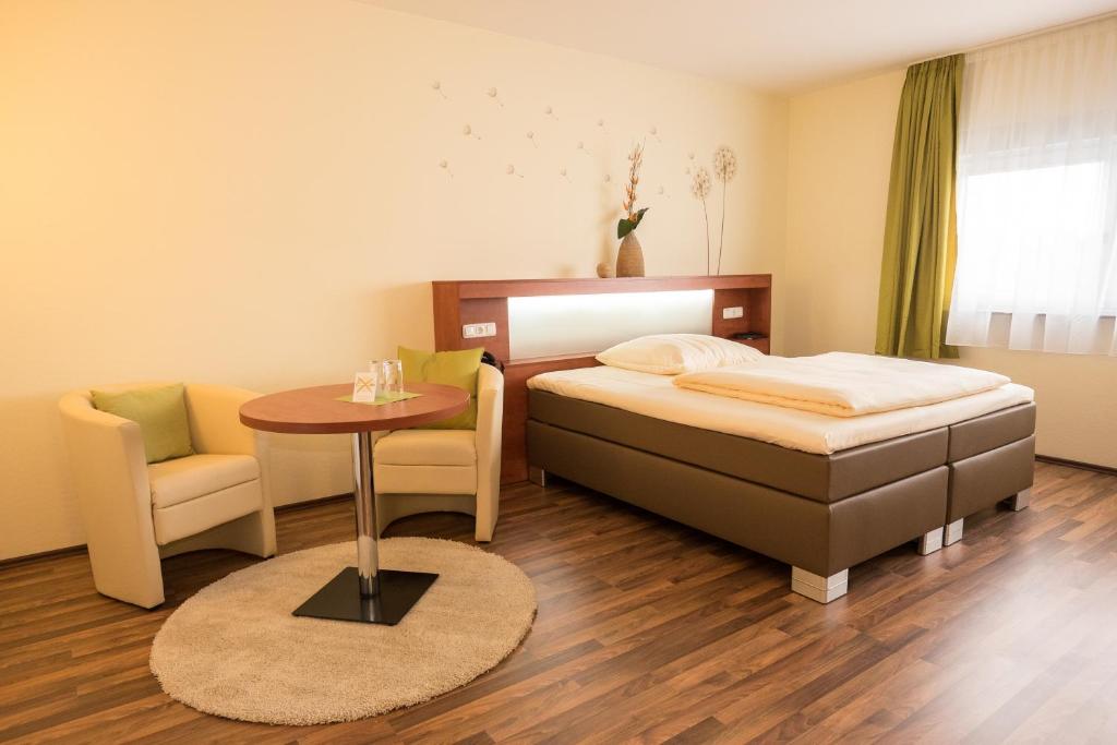 美因河畔霍海姆维奥拉酒店的卧室配有1张床、1张桌子和1把椅子
