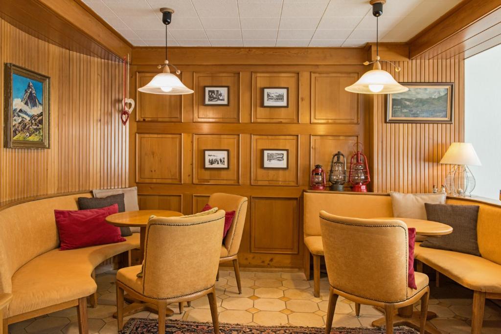 采尔马特Hotel Alpina的一间在房间内配有桌椅的餐厅