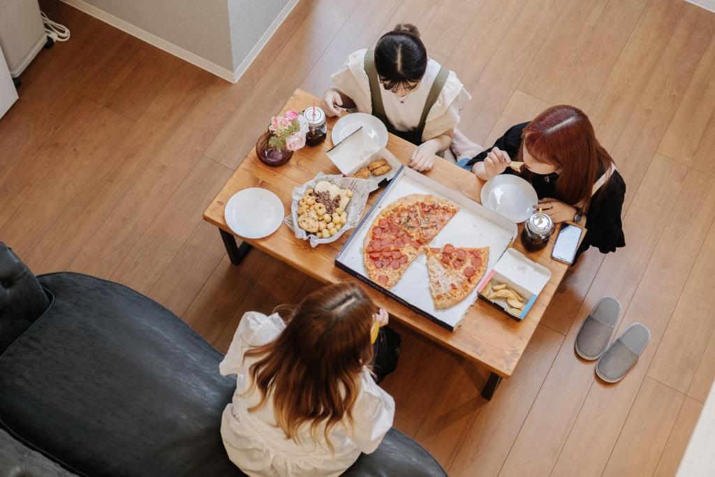 熊本REQRAS Sakuramachi - Vacation STAY 45081v的一群坐在餐桌旁吃比萨饼的人