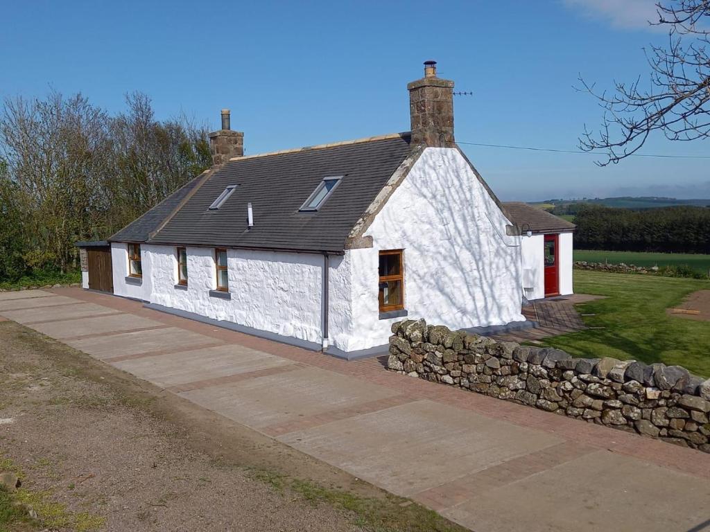 彼得黑德Meikle Aucheoch Holiday Cottage, plus Hot Tub, Near Maud, in the heart of Aberdeenshire的前面有石墙的白色房子